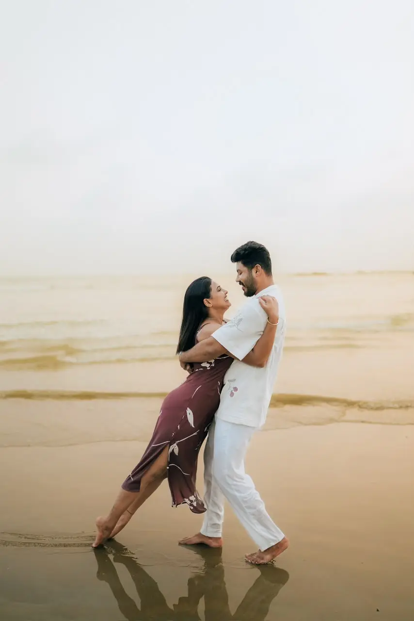 A couple embracing barefoot at the water's edge on a beach